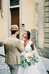 Side view of couple standing against building