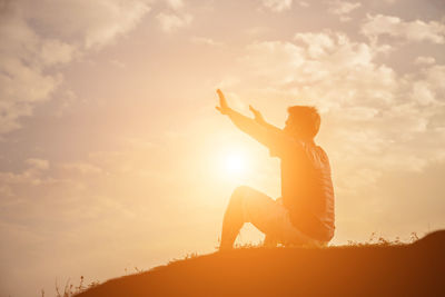 Side view of silhouette woman sitting against sky during sunset