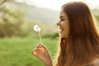 Close-up of woman blowing dandelion