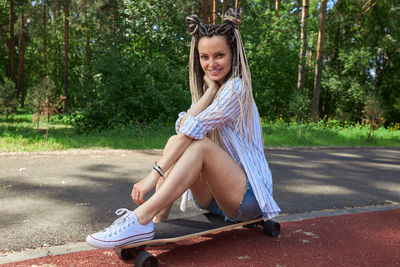 Young woman smiling while sitting on skateboard