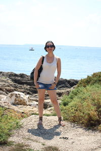 Full length of man standing on rock by sea against sky