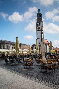 Clock tower at sidewalk cafe against sky