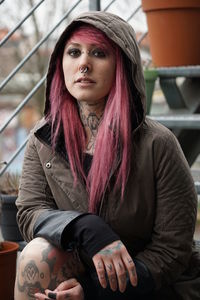 Portrait of woman with pink hair and hooded shirt