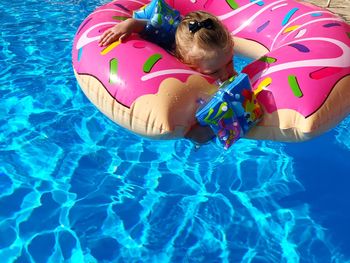 High angle view of child floating in swimming pool