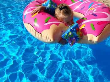 High angle view of girl floating in swimming pool with inflatable ring