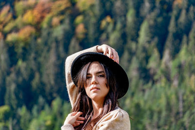 Portrait of beautiful young woman standing against plants