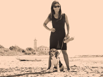 Portrait of woman with dog standing at landscape against clear sky