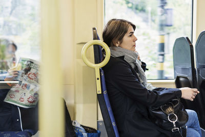 Side view of young woman sitting in tram