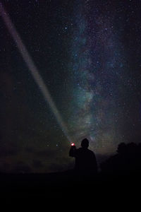 Silhouette man standing against star field at night