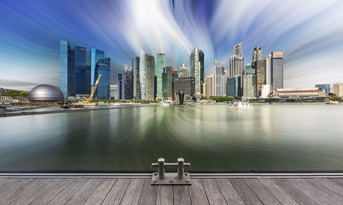 Modern buildings by river against sky in city