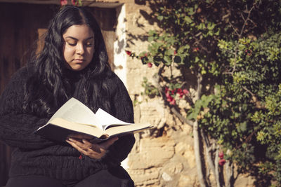 Portrait of young woman standing against plants