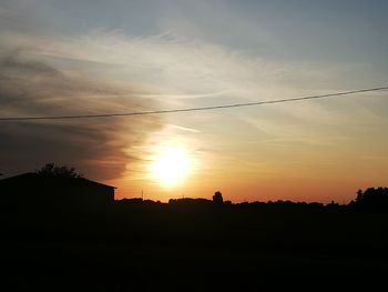 Silhouette trees on field against sky at sunset