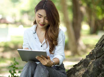 Midsection of young woman using digital tablet at park