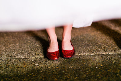 Low section of woman wearing red sequin shoes standing on footpath