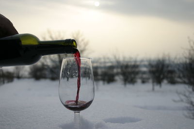 Close-up of red wine being poured in glass during winter
