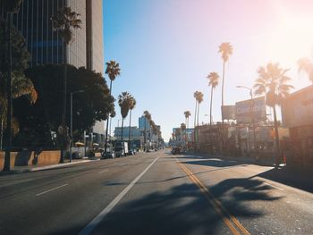 Road by buildings in city against sky