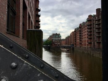 Canal amidst buildings in city against sky