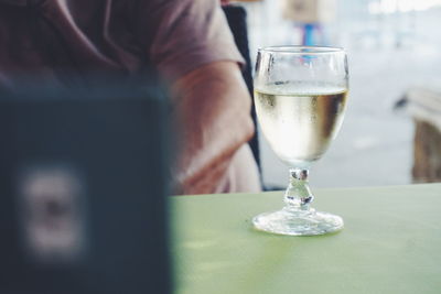 Midsection of man sitting by white wine on table