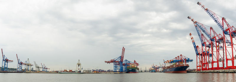 Cranes at commercial dock against sky