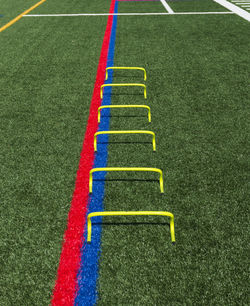 Six yellow mini hurdles lined up in a straight line on a turf field for speed and agility training.