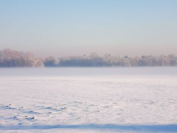 Frozen lake against clear sky during winter