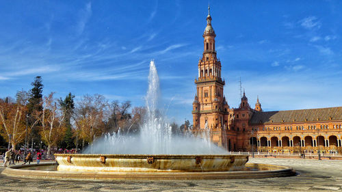 Fountain in front of historic building against sky