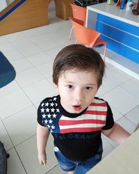 Portrait of cute boy sitting on tiled floor