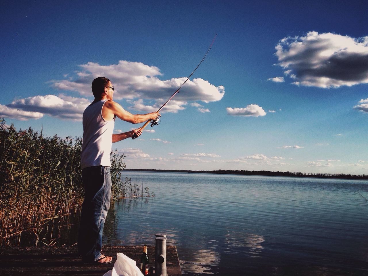 water, sky, lifestyles, leisure activity, casual clothing, person, lake, standing, full length, young adult, nature, three quarter length, tranquility, beauty in nature, cloud - sky, holding, blue, sea