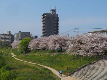 People walking on footpath by buildings against sky