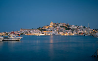 Buildings of ibiza city by sea against clear sky after sunset