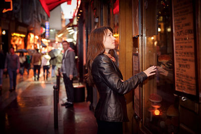 Attractive woman in a black jacket stands near the shop window