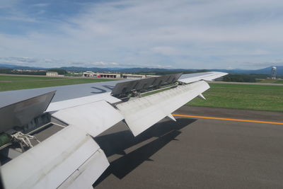 Airplane flying over airport runway against sky