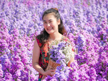 Portrait of a smiling young woman against purple flowering plants