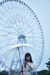 Portrait of woman with ferris wheel against sky