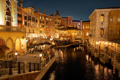 Canal amidst buildings in city at night