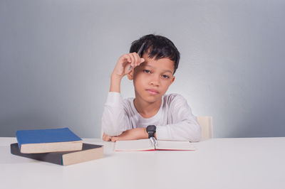 Portrait of boy sitting on table against wall