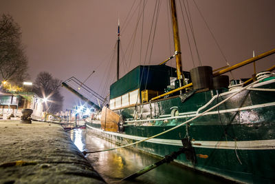 Sailboats moored at harbor against sky at night