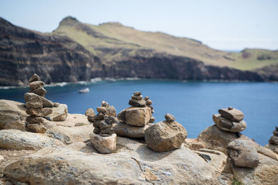 Stack of rocks by lake against sky