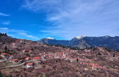 Aerial view of townscape by mountain against sky