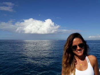 Portrait of smiling woman against sea on sunny day