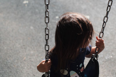 High angle view of girl playing on swing at playground