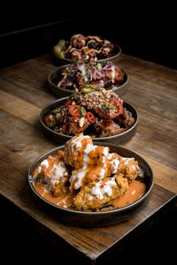 High angle of appetizing crispy chicken with sauces placed near plated with chicken wings in bbq sauce served with vegetables on wooden table in restaurant