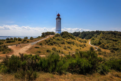 Lighthouse amidst trees and buildings against sky