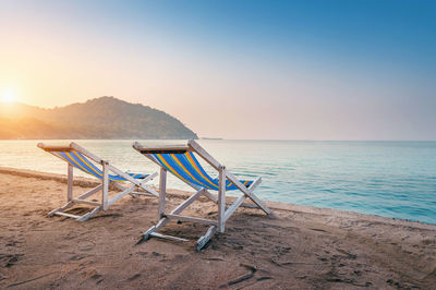 Deck chairs at beach against clear sky