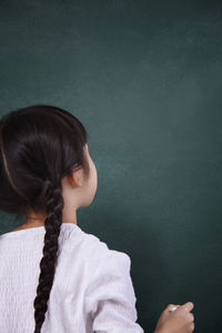 Rear view of girl writing on blackboard