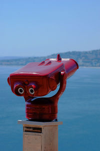Close-up of coin-operated binoculars by sea against clear sky