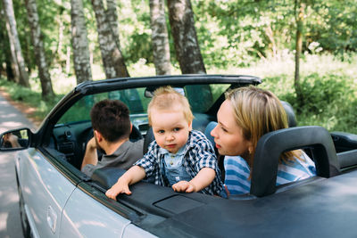 Mom, dad and little son in a convertible car. summer family road trip to nature