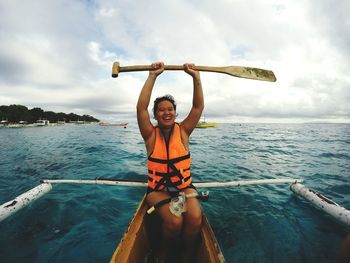 Cheerful mid adult woman sailing outrigger on sea