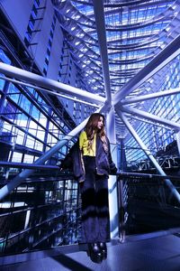 Low angle view of woman standing on footbridge