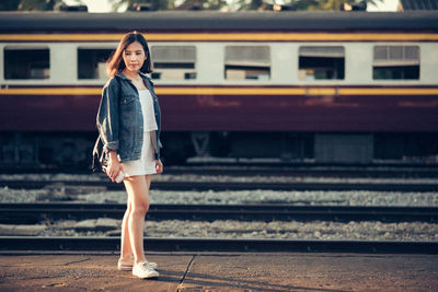 Young woman standing at railroad station